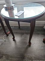 Angled view of one table showing cabriole legs, glass top in place