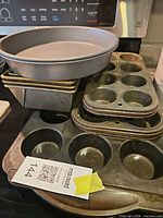 Stack of round cake pan, four loaf pans, three muffin tins on stovetop