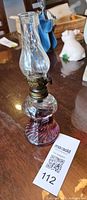 Angled view showing complete lamp with purple glass base, brass burner and clear chimney