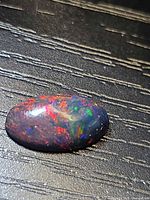 Black opal cabochon showing multicolour play