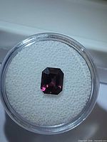 Electric purple pink spinel in plastic gem case, top view