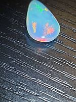 Crystal opal showing multicolored flashes on dark background