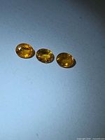 Three oval orange sapphires on light background