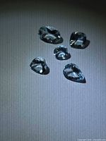 Five light blue faceted aquamarine stones on neutral background