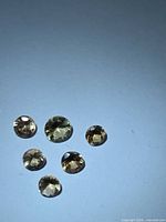 Six round faceted champagne-orange gemstones on light background