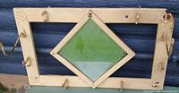 Full view of metal coat rack, hooks, diamond glass panel