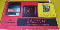 All three paper products displayed: XL sketch pad, Hilroy notebook, Fredrix canvas pad