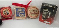 Three sealed coaster packs and boxed miniature stein displayed together