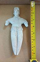 Front view of ceramic figure beside tape measure showing height