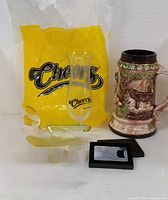 Group shot of Cheers glass, ceramic stein, Carlsberg opener and yellow Cheers bag