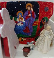 Group shot showing nativity wall hanging, angel, gingerbread container, candle, snowman figurine