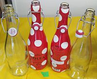 Four swing-top bottles lined up, clear and red polka dot designs visible