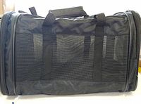 Full side view of black soft-sided carrier showing mesh panel, handles and end zippers