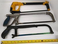 Three hacksaws laid out with measuring tape for scale