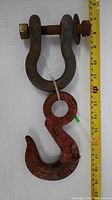 Full view of bow shackle attached to Crosby safety hook with measuring tape for scale