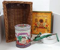 Group shot of all five items: wicker basket, decorative tin, recipe binder, apple peeler resting in ceramic dish