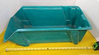 Full view of one green fiberglass bin with tape measure showing length ~29 in