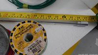 Magnet wand beside measuring tape showing ~24 in length, green wire spool visible