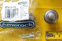 Amerock BP4258-WN knob beside original bag, barcode, and screw, measurement tape showing 1 inch diameter