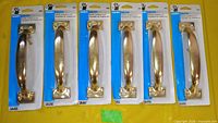 Six Handy Helper 6.5 in brass door handles in retail packaging