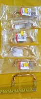 Six sealed Onward gold drawer handles with screws on yellow background