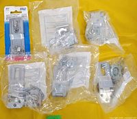 Six packaged hasps on yellow background, five in clear plastic, one in retail card