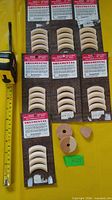 Seven sealed packages of Ornamental curved mouldings beside measuring tape and loose wooden plugs