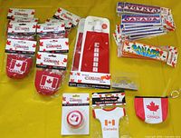 Group of packaged Canada souvenirs including erasers, water bottle, yo-yo, cozies, metal card holder, cell phone holder, coin purse and drink pouches