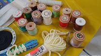 Close-up of thread spools, yarn, elastic and seam ripper