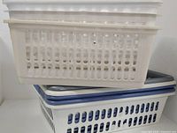 Stack of white baskets on white laundry basket with grey lid visible