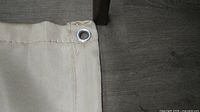 Corner of beige welding blanket showing stitched hem and metal grommet