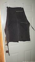 Dark brown apron with multiple pockets hanging on door