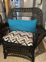 Front view of black wicker armchair with cushions