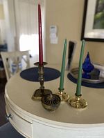 Group shot showing tall candlestick, two low candlesticks with green tapers, and incense burner with lid