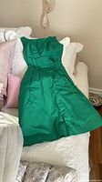 Full view of green cocktail dress laid flat on bed