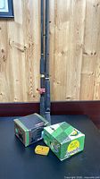 Two graphite rods, two reel boxes and yellow hook tin on table