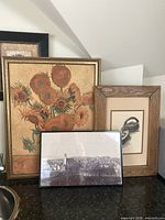 Three framed prints: sunflower still life, iron illustration, cityscape photograph