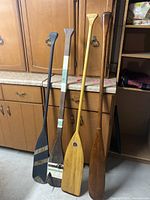Four paddles leaning against cabinet showing full length and different finishes