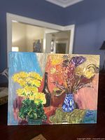 Full view of signed floral still life painting on table