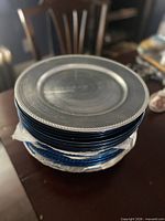 Stack of assorted plastic charger plates showing silver plate on top and blue plates beneath