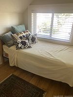 Twin bed against wall under window, showing full frame, headboard, mattress