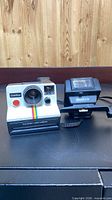 Front view of Polaroid OneStep Land camera beside Keystone 610 flash