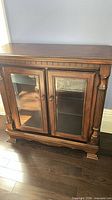 Front view of dark brown cabinet with twin glass doors and fluted side columns