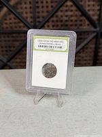 Front view of coin inside labelled slab on stand