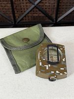 Compass and pouch side-by-side on table