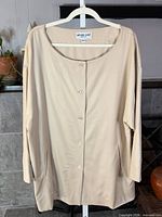 Front view of beige Michael Kors button-up jacket on hanger showing full length, buttons, pockets and neckline