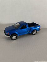 Passenger-side three-quarter view showing blue Ford F-150 model pickup