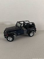 Front left perspective of black open-top Jeep Wrangler Rubicon model