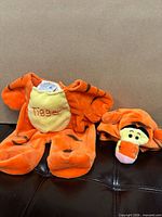 Two-piece orange striped Tigger outfit laid flat, including jumpsuit and hood