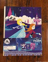 Front view of packaged set of three Frozen composition notebooks with band label